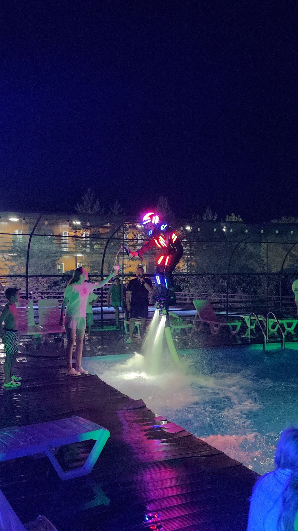 LED-suited flyboard pilot hovering over a hotel pool at night in Phuket