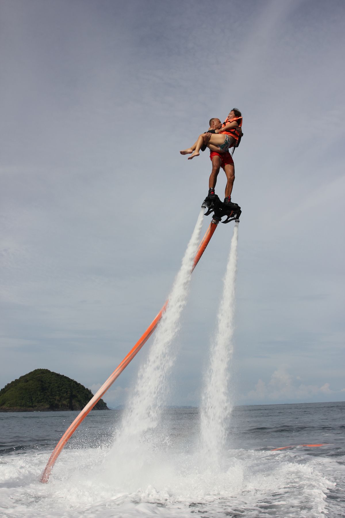 Tandem flyboard flight over the Andaman Sea off Phuket with a tropical island behind